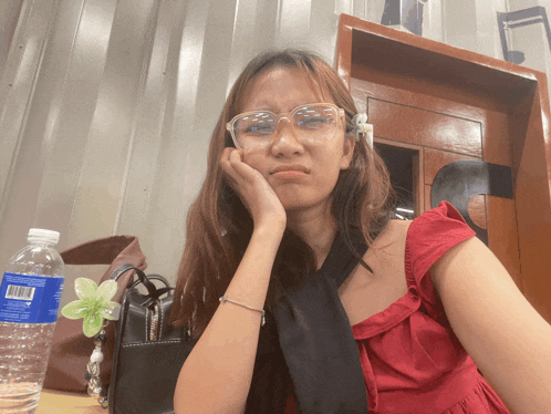 a bottle of aquafina water sits on a table next to a woman wearing glasses