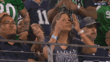 a woman in a dallas cowboys shirt is covering her face