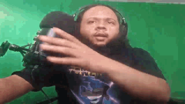 a man with a beard is wearing headphones and holding a can of soda in front of a microphone .