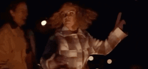 a woman is pointing at something in the dark while standing next to another woman .