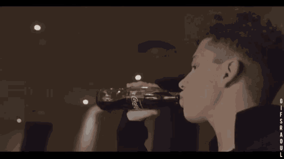 a young man holding a bottle with the word gif on the bottom right corner