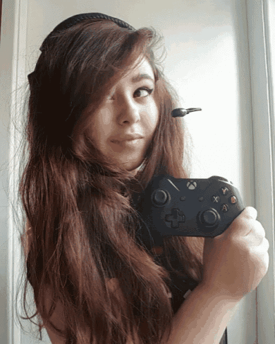 a woman with long hair is holding a video game controller in her hand