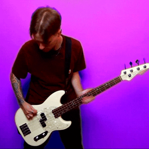 a man playing a white bass guitar with a purple background