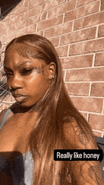 a woman with long brown hair is standing in front of a brick wall and the caption says really like honey