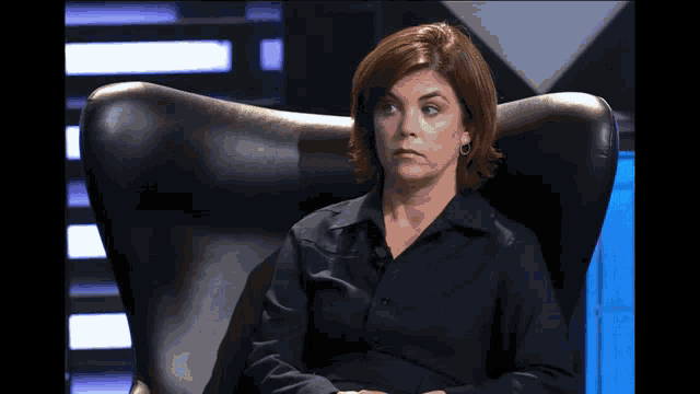 a woman sits in a black chair with her eyes closed