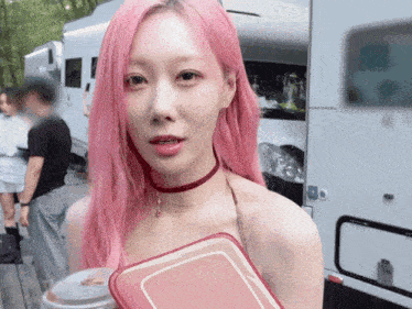 a woman with pink hair and a red choker is holding a red container