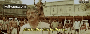 a man with a mustache is standing in front of a crowd of people and says dinchutha dinchutha ra .