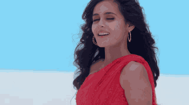 a woman in a red one shoulder dress is smiling with her eyes closed