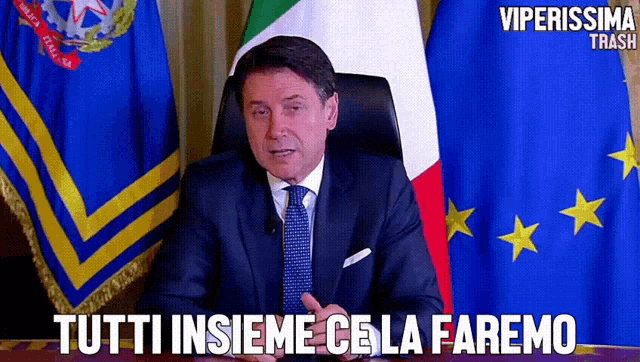 a man in a suit and tie is sitting in front of flags with the words tutti insieme cela faremo above him