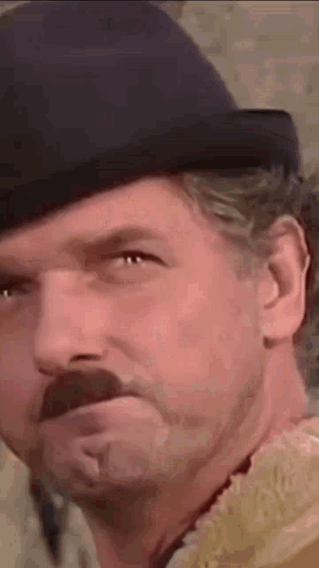 a man with a hat and mustache is making a face .