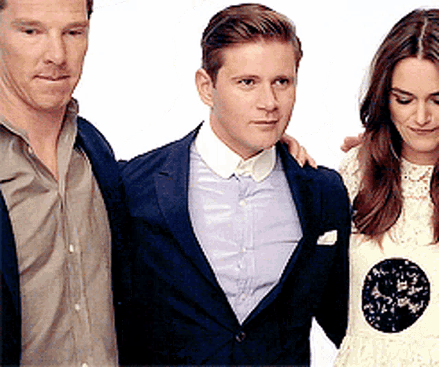 a man in a suit is standing next to two other people