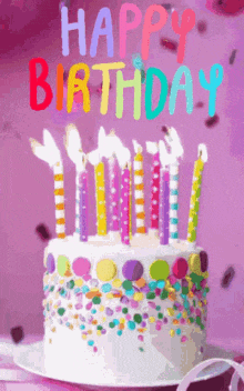 a birthday cake with candles and sprinkles and the words happy birthday on it