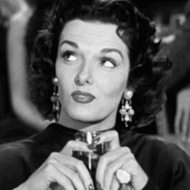 a woman with a ring on her finger holds a glass of wine