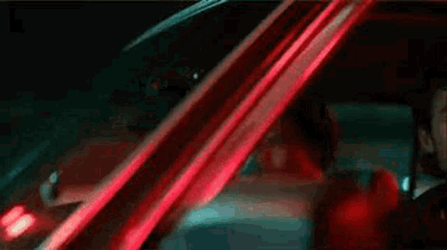 a man is driving a car at night with a red light on the side of the car .