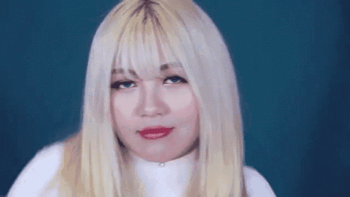 a woman with blonde hair and red lipstick is making a funny face against a blue background .