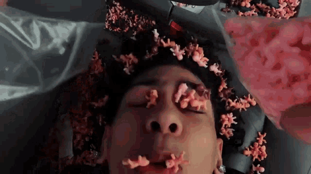 a man is laying in a pile of pink toys on his face
