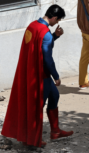 a man in a superman costume is giving a thumbs up sign