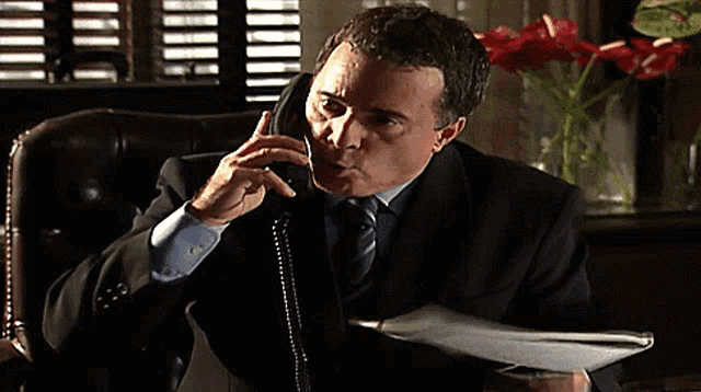a man in a suit and tie talking on a phone