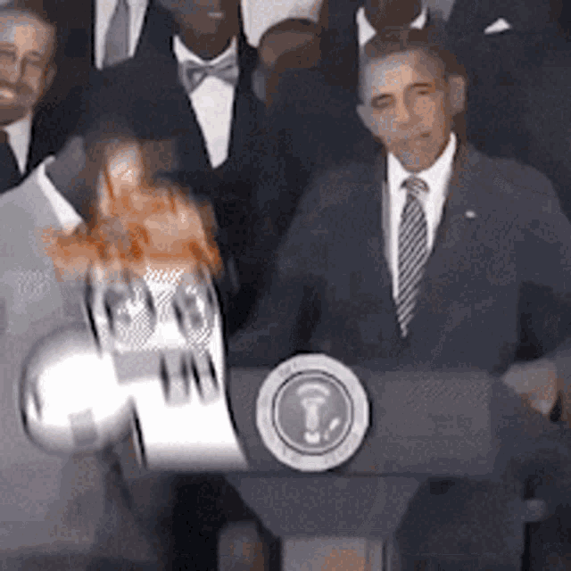 a man in a suit and tie stands at a podium with a globe in front of him