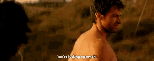 a man without a shirt is talking to another man in a field .