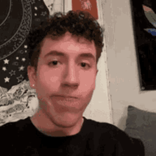 a young man with curly hair is making a funny face in a living room .
