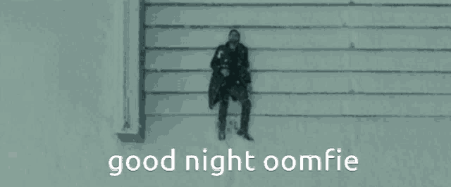 a man sitting on a wall with the words good night oomfie