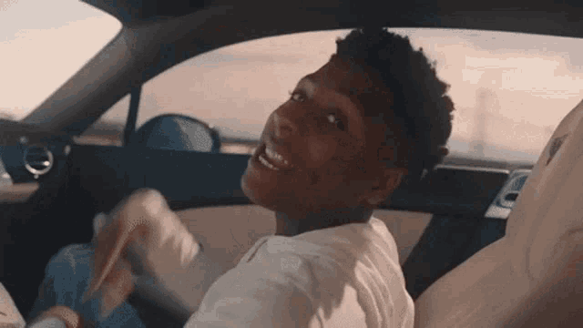 a young man is sitting in the back seat of a car and smiling .