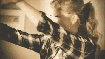 a woman in a plaid shirt is dancing with her arms in the air .