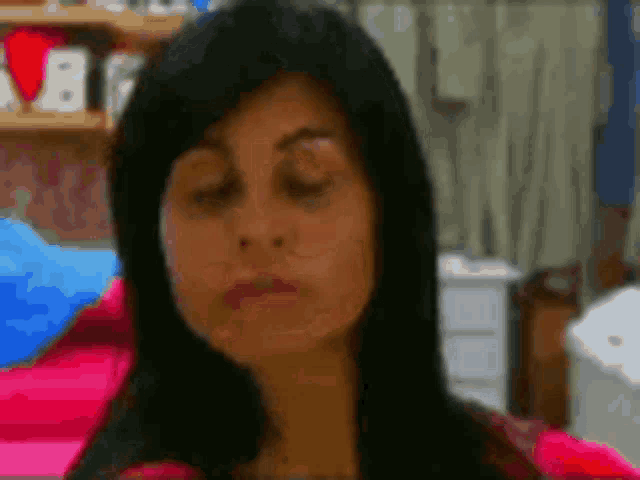 a close up of a woman 's face with her eyes closed in a room .