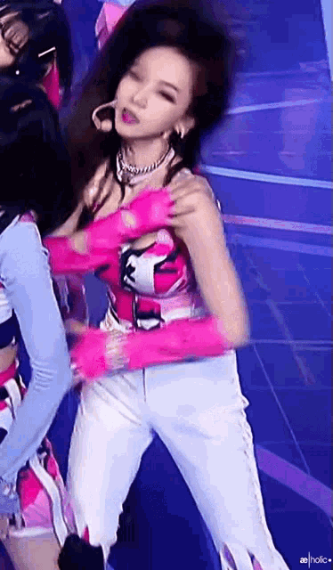 a woman in a pink top and white pants is dancing on stage .