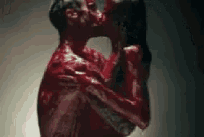 a man and a woman are kissing in a room covered in blood .