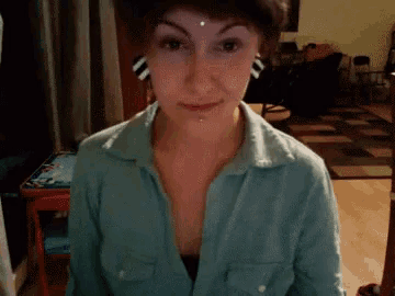 a woman wearing a blue shirt has a piercing in her nose