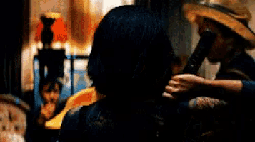 a woman with a tattoo on her arm is holding a sword in a dark room .