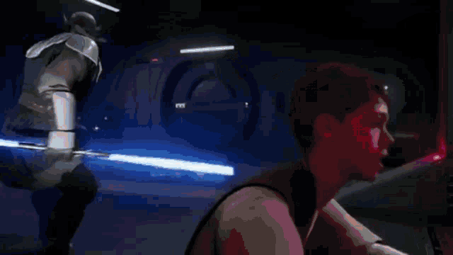 a man is holding a light saber in a dark room and talking to another man .