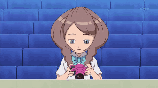 a cartoon girl is holding a pink camera in front of a row of blue seats that says tokyo