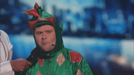 a man in a green and red dragon costume is talking into a microphone