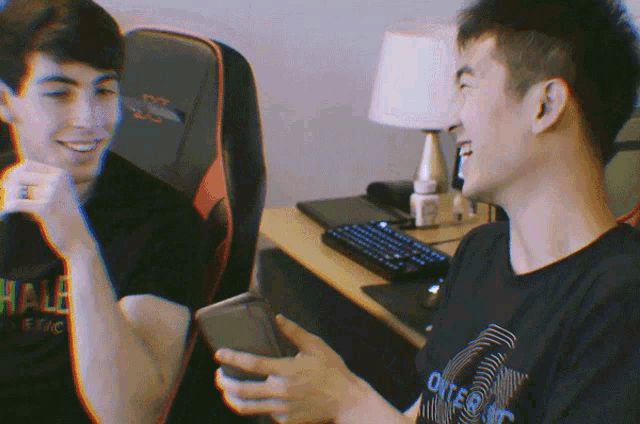 a man wearing a black shirt with the word outer on it looks at his phone