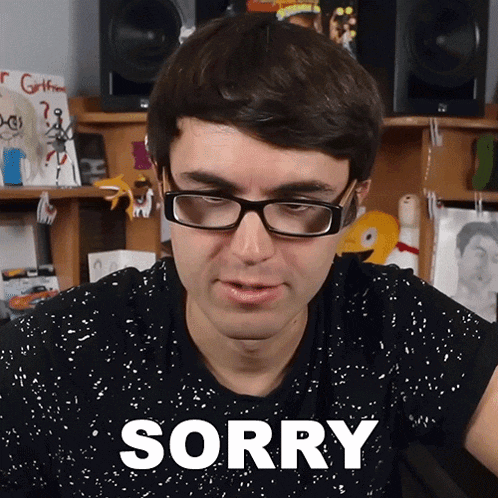 a man wearing glasses says sorry in front of a desk