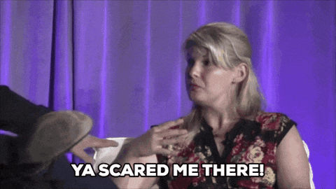 a woman is sitting in front of a purple curtain and says ya scared me there