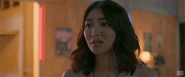 a close up of a woman 's face with a surprised look on her face in a dark room .