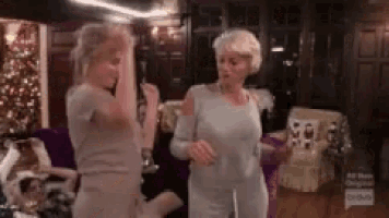 two women are dancing in a living room .