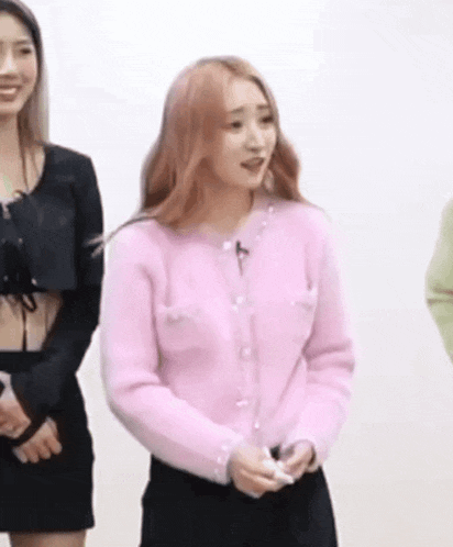 a woman in a pink cardigan is standing in front of a group of women .
