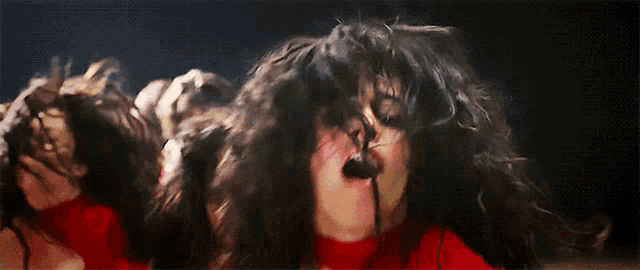 a close up of a woman 's face with her mouth open and her hair blowing in the wind .