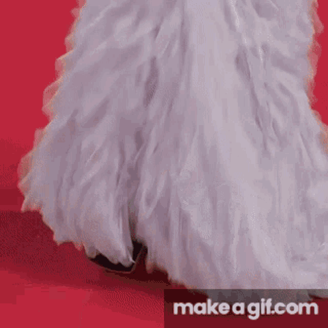 a woman in a white dress is walking on a red carpet