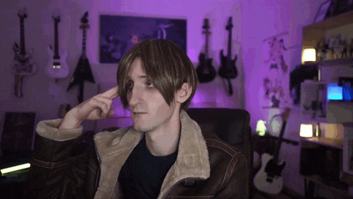 a man wearing a brown jacket is sitting in front of a purple wall with guitars on it