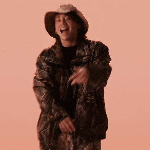 a man wearing a cowboy hat and a camo jacket is dancing