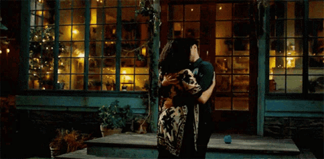 a man and woman are hugging in front of a building
