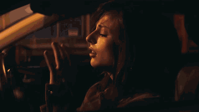 a woman driving a car with her eyes closed and her hand on her face