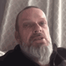 a man with a beard is making a funny face while looking at the camera .
