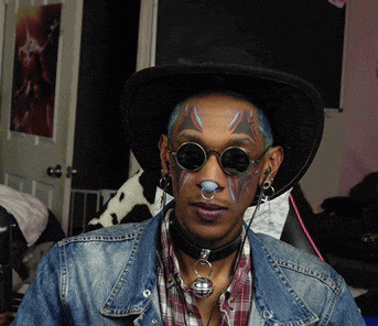 a man wearing a cowboy hat and sunglasses has a bell on his neck